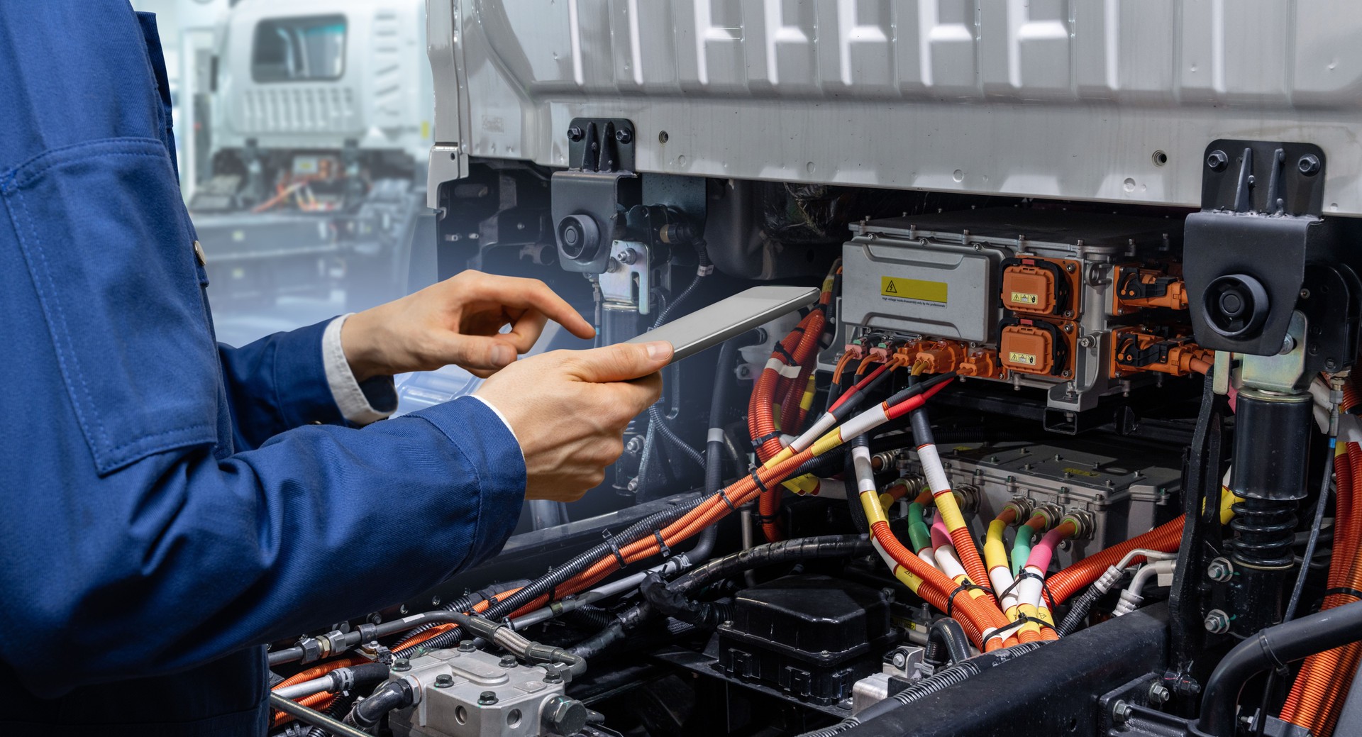 Serviceman with digital tablet next to electric truck