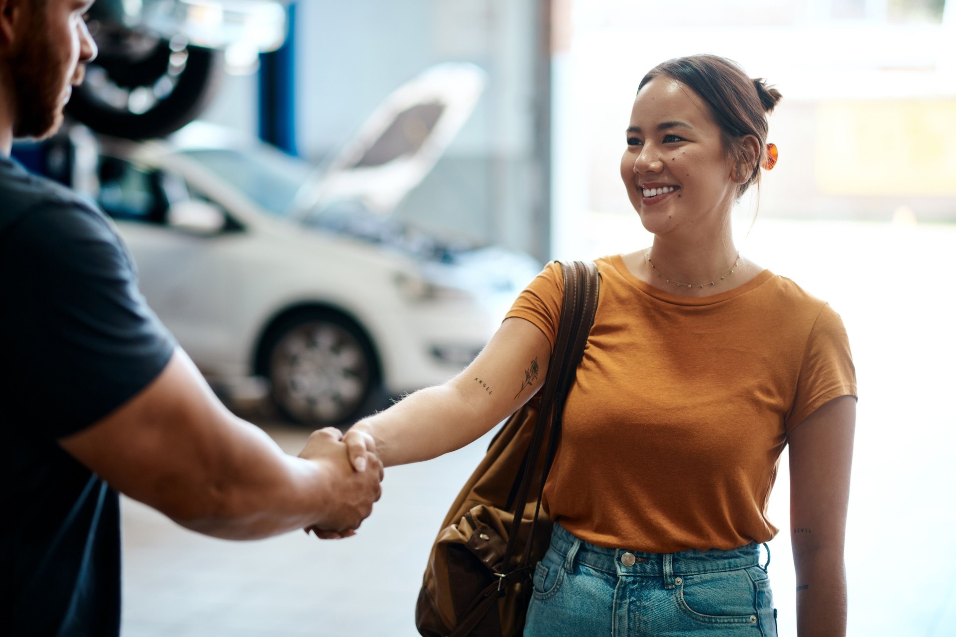 Shot of a woman shaking hands with a mechanic in an auto repair shop